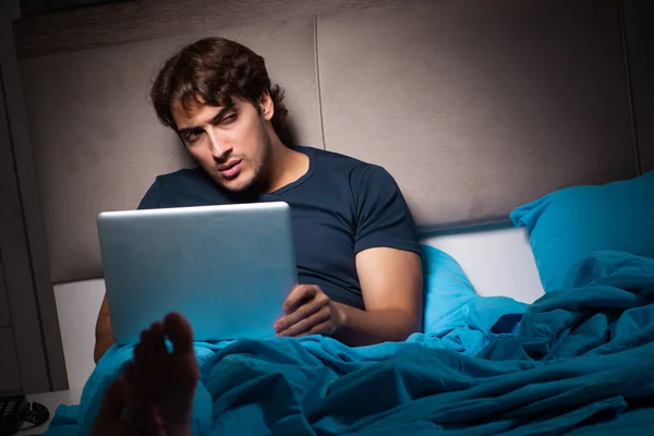 Uomo che lavora sul computer portatile di notte a letto — Foto Stock