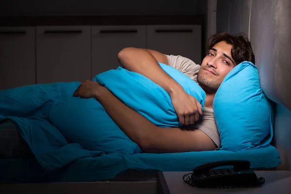 Young handsome man suffering from insomnia in bed — Stock Photo, Image