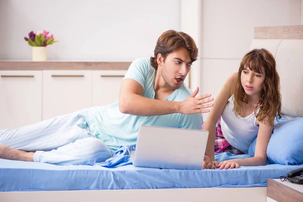 Pareja joven con portátil en el dormitorio — Foto de Stock