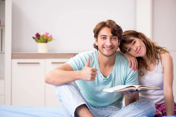 Pareja joven con libro en el dormitorio — Foto de Stock