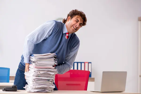 Joven empleado guapo infeliz con el trabajo excesivo — Foto de Stock