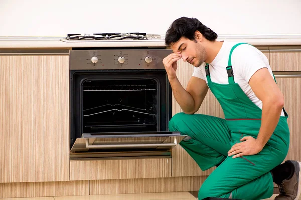 Jungunternehmer repariert Ofen in Küche — Stockfoto