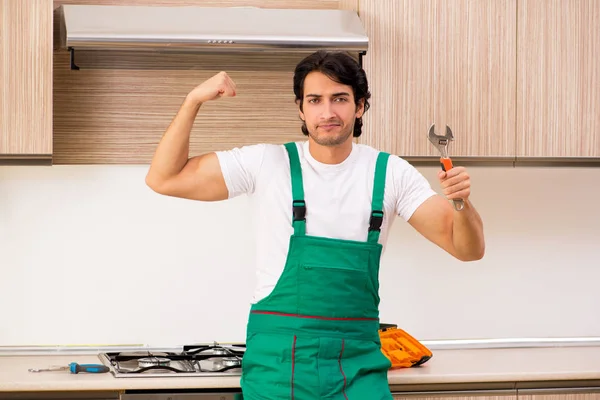 Young contractor repairing oven in kitchen