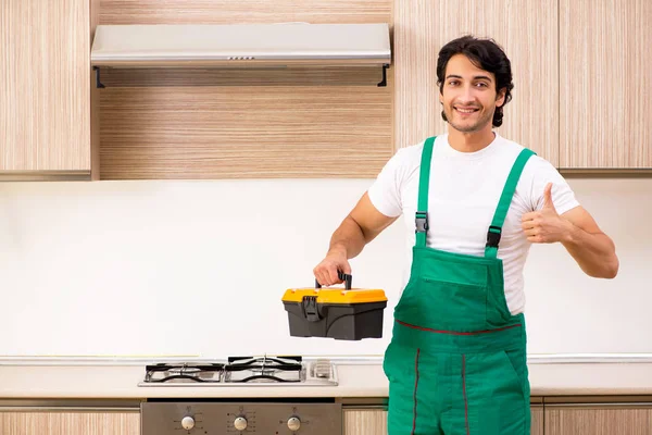 Jovem empreiteiro reparação forno na cozinha — Fotografia de Stock