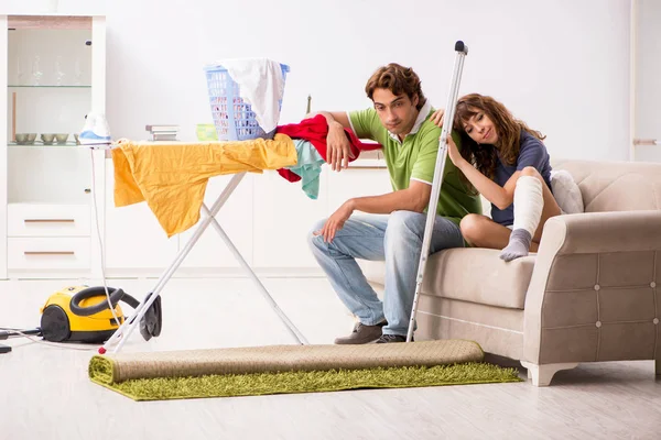 Husband helping leg injured wife in housework — Stock Photo, Image