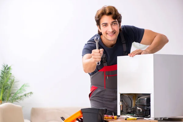 Junger hübscher Bauunternehmer repariert Kühlschrank — Stockfoto