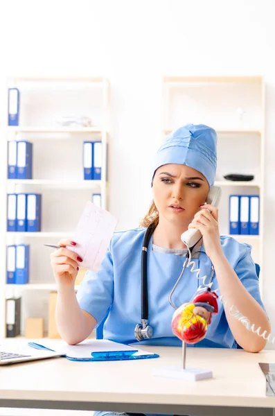 Молодая женщина-врач кардиолог сидит в больнице — стоковое фото