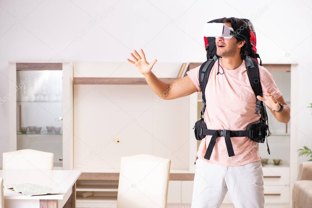 Young male tourist with virtual glasses preparing for trip 
