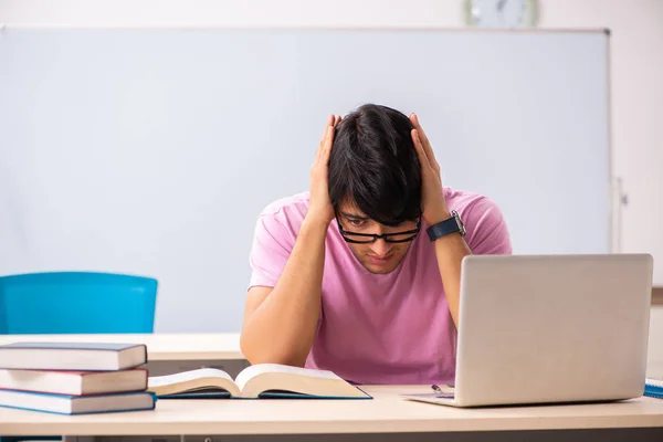 Giovane studente maschio seduto in classe — Foto Stock