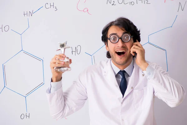Young funny chemist in front of white board — Stock Photo, Image