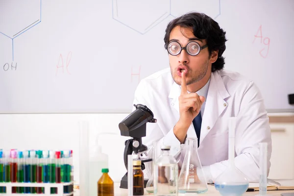 Молодий смішний хімік перед білою дошкою — стокове фото