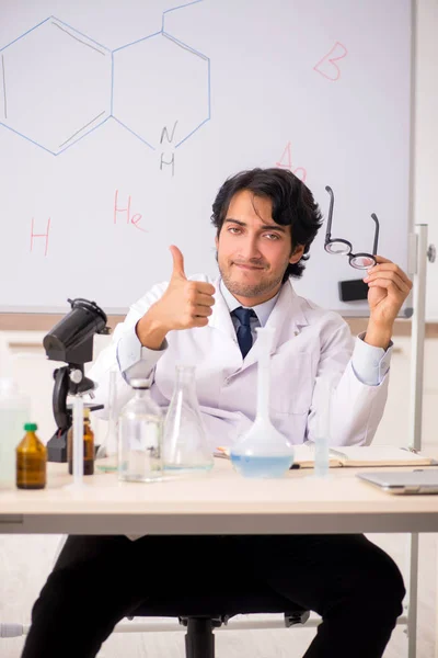 Young funny chemist in front of white board — Stock Photo, Image