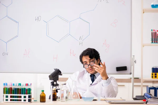 Young funny chemist in front of white board — Stock Photo, Image