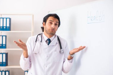 Genç doktor beyaz tahtanın önünde. 