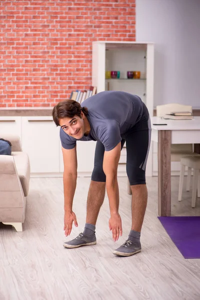 Joven hombre guapo haciendo ejercicios deportivos en casa —  Fotos de Stock