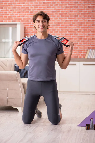 Joven hombre guapo haciendo ejercicios deportivos en casa —  Fotos de Stock