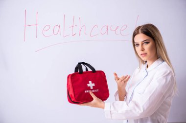 Genç bayan doktor beyaz panonun önünde duruyor. 