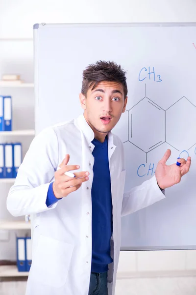 Молодой химик стоит перед доской — стоковое фото