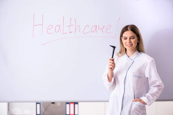 Młoda lekarka stojąca przed białą tablicą — Zdjęcie stockowe