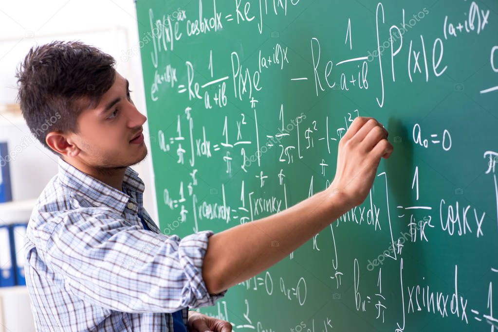 Young male student studying math at school