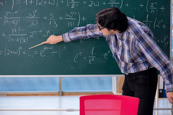 Joven profesor de matemáticas divertido delante de pizarra —  Fotos de Stock