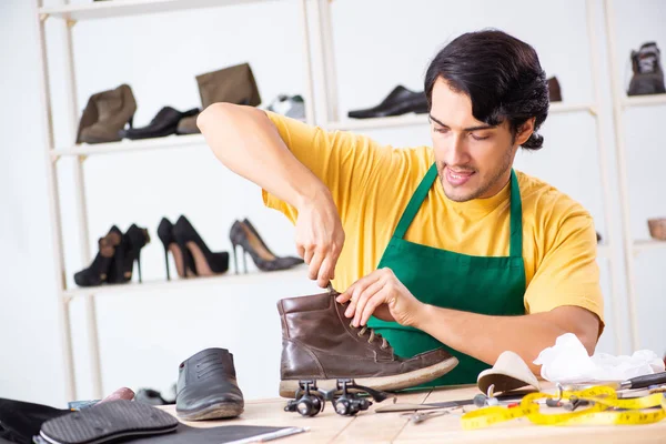 Ung man reparera skor i verkstad — Stockfoto