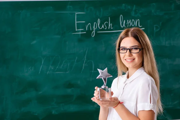 Jonge vrouwelijke Engels leraar staande voor de b — Stockfoto