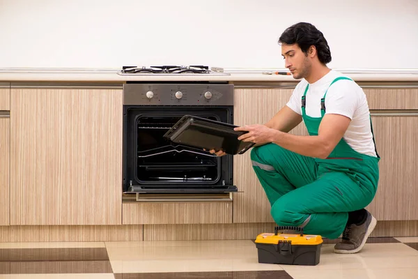 Joven contratista reparación de horno en la cocina —  Fotos de Stock