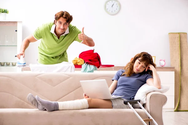 Mari aider femme blessée jambe dans les travaux ménagers — Photo