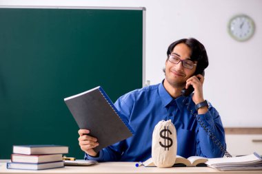 Tahtanın önünde genç bir erkek öğretmen.  