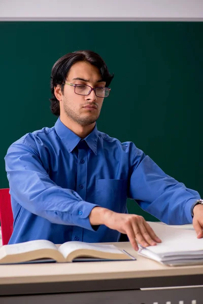 Young male teacher in front of chalkboard — Stock Photo, Image