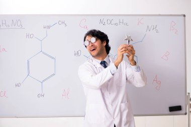 Beyaz tahta önünde genç komik kimyager 