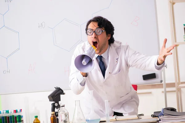 Молодой смешной химик перед белой доской — стоковое фото