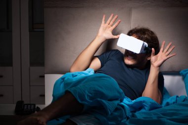 Genç adam, gece yatakta ile bilgisayar oyunu oynamak