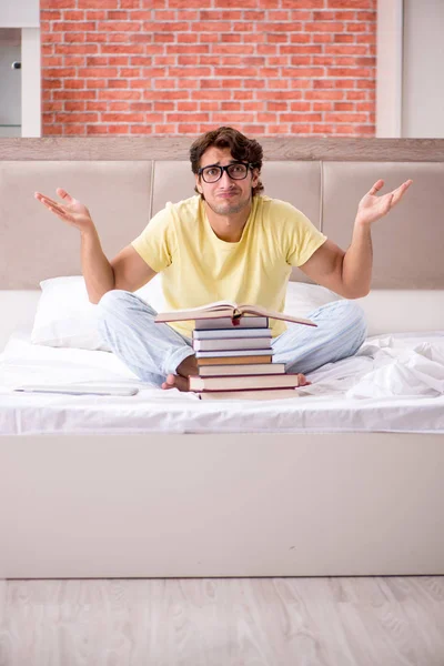 Νεαρός φοιτητής που σπουδάζει στο κρεβάτι για τις εξετάσεις — Φωτογραφία Αρχείου