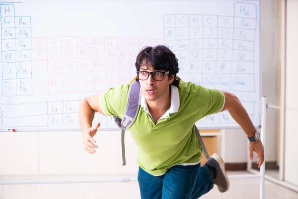 Jovem estudante químico na frente da tabela periódica — Fotografia de Stock