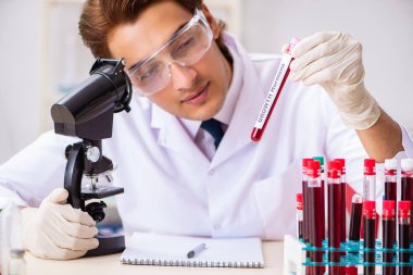 Genç yakışıklı laboratuvar asistanı hastanede kan örnekleri test ediyor. 