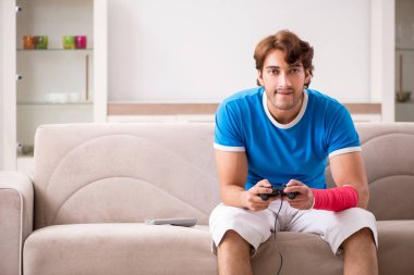 Yaralı kollu kanepede oturan genç adam 