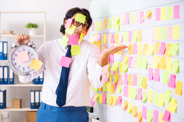 Young employee in conflicting priorities concept 