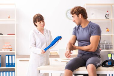 Genç erkek hasta, kadın doktor travmatoloğu ziyaret ediyor. 