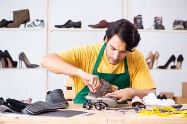 Genç adam ayakkabı atölyesinde tamir 