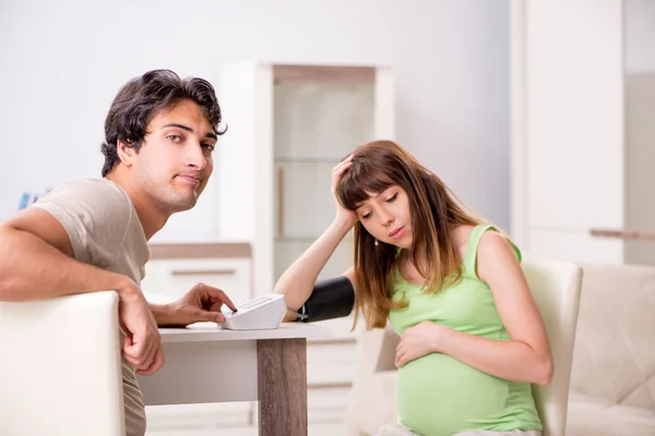 Чоловік перевіряє вагітні дружини артеріальний тиск — стокове фото
