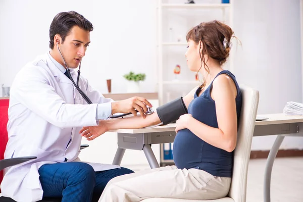 Jovem médico verificando a pressão arterial das mulheres grávidas — Fotografia de Stock