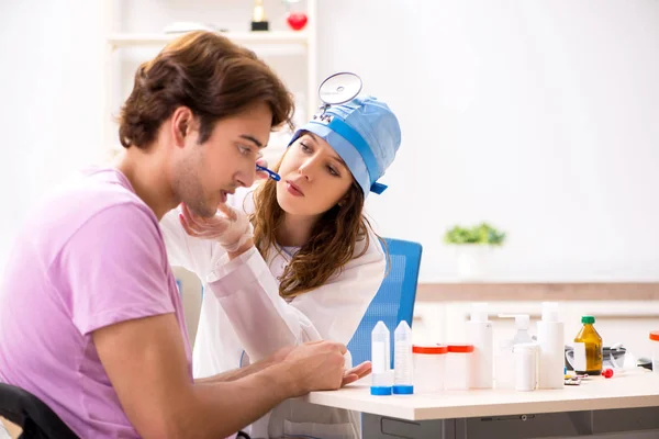 Joven hombre guapo visitando joven médico otorrinolaringólogo —  Fotos de Stock