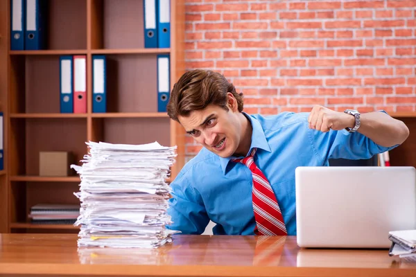 オフィスに座って過剰な仕事を持つ若い従業員 — ストック写真