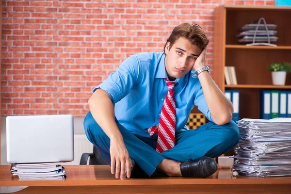 Jeune employé ayant un travail excessif assis au bureau — Photo