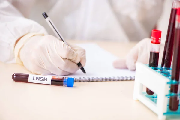 Asistente de laboratorio joven guapo analizando muestras de sangre en el hospital — Foto de Stock