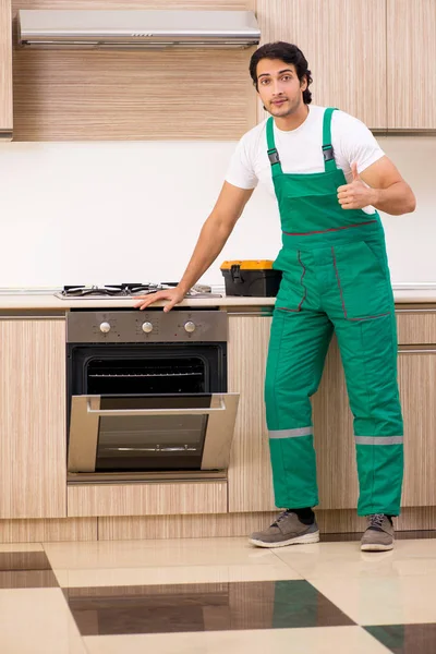 Young contractor repairing oven in kitchen