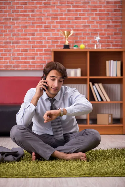 Young handsome employee doing yoga in the office