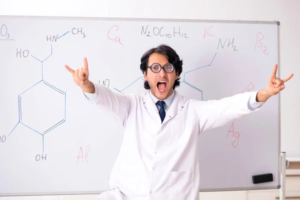 Молодий смішний хімік перед білою дошкою — стокове фото